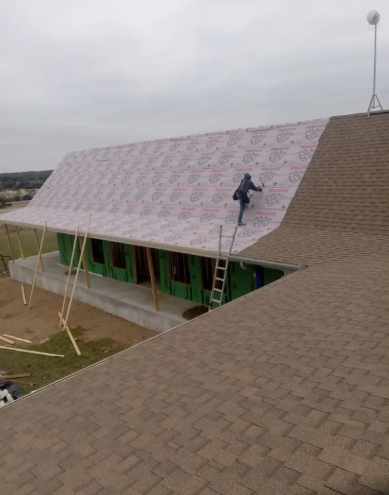 Worker preparing underlayment for a metal roof installation in Itasca